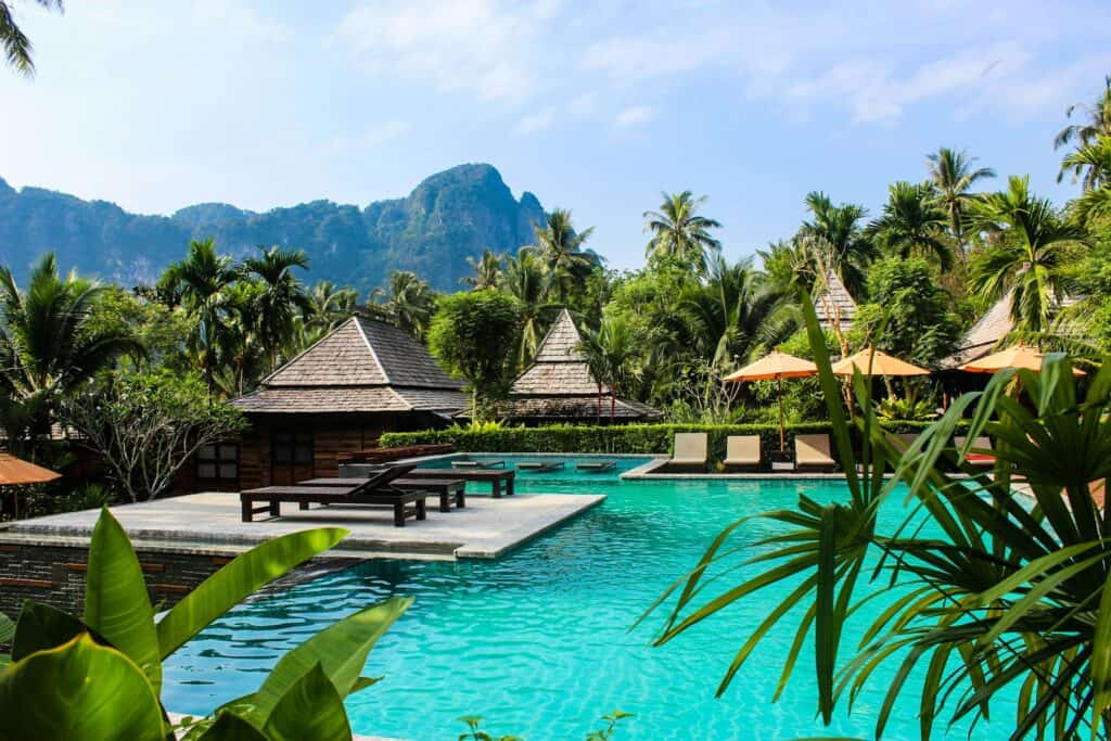 Luxurious pool surrounded by lush tropical greenery and traditional Thai-style villas.