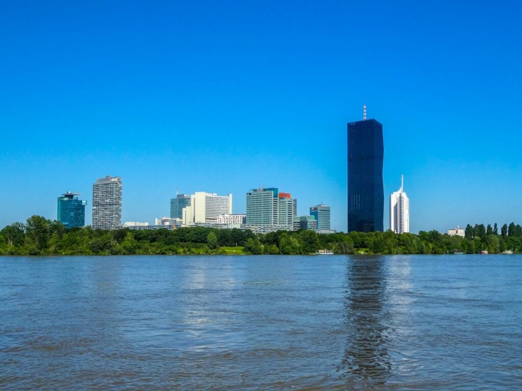 City skyline with skyscrapers and a river under a clear blue sky.