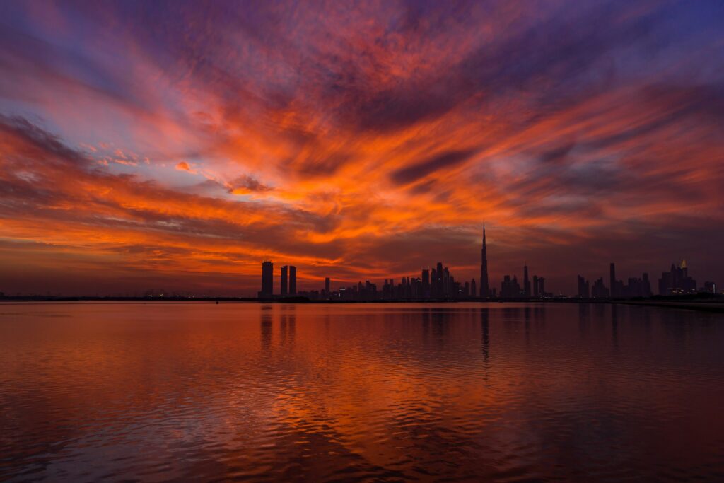 Dubai skyline at dusk with Burj Khalifa and city lights reflected on the water