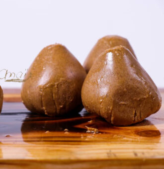 Truffes en chocolat brun sur planche en bois, fond blanc.