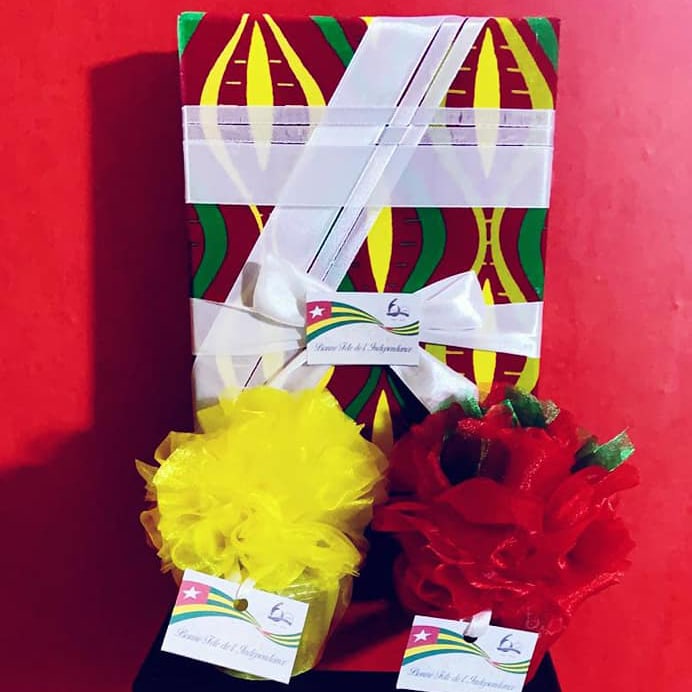 Palette cadeau colorée avec ruban blanc et étiquettes sur fond rouge vibrant.