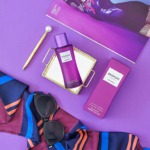 Bouteille de parfum BESPOKE pour femme avec accessoires de mode et produits de beauté, sur fond violet.