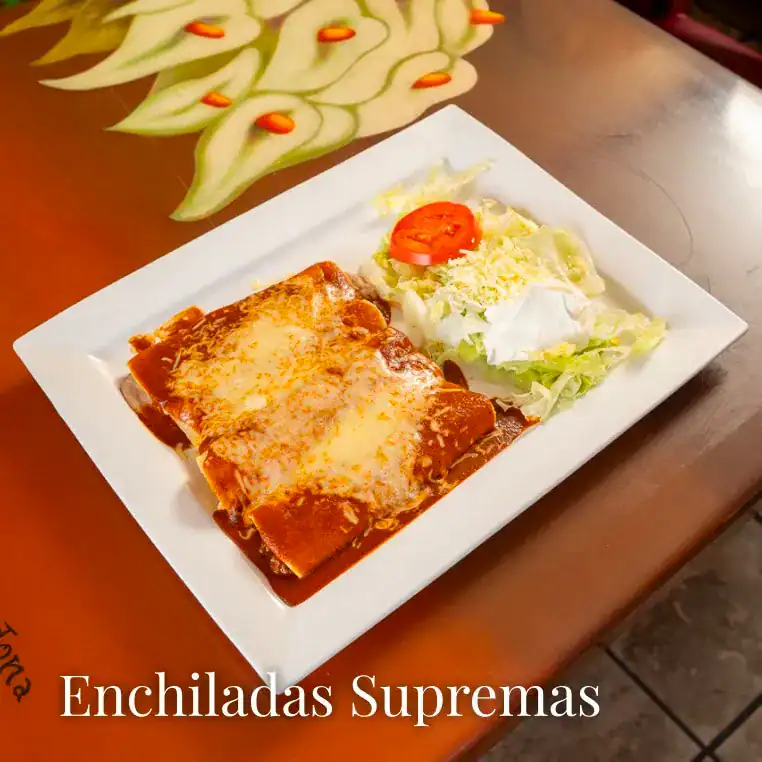 Delicious cheesy enchiladas served with fresh salad on a white plate. Perfect for a satisfying Mexic.