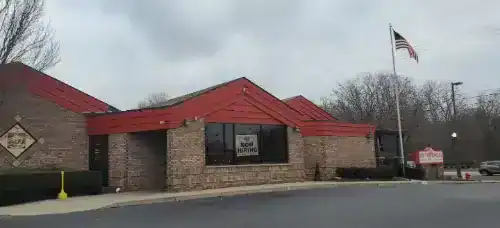 Exterior view of a building with a red roof and brick walls, featuring a "Rename Website" sign, unde.