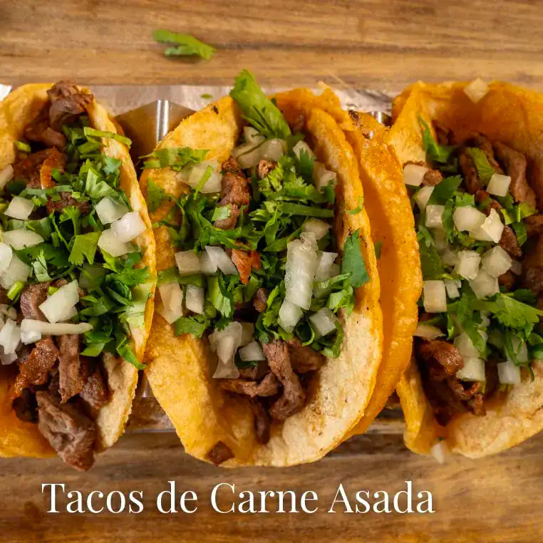 Delicious carne asada tacos topped with chopped onions and cilantro, served in crispy taco shells fo.