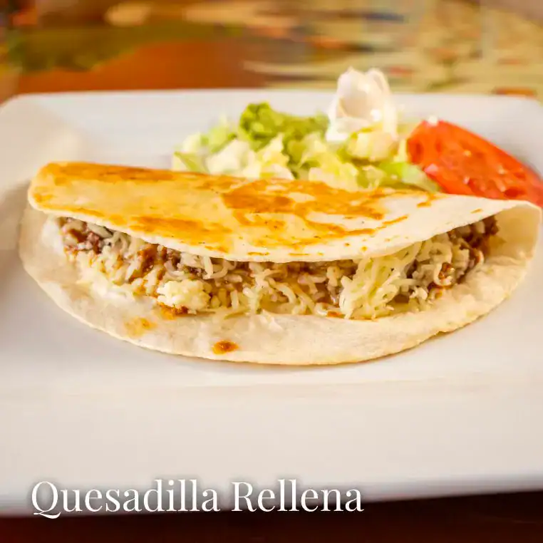 Delicious quesadilla filled with shredded meat, melted cheese, and served with fresh salad and tomat.