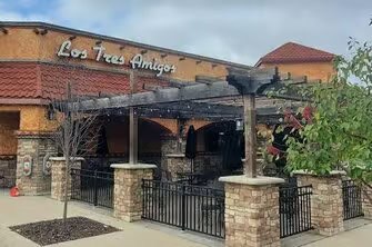 Exterior view of a restaurant with a rustic brick facade and wooden pergola.