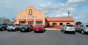Front view of a restaurant with parking lot and cars in a suburban area.