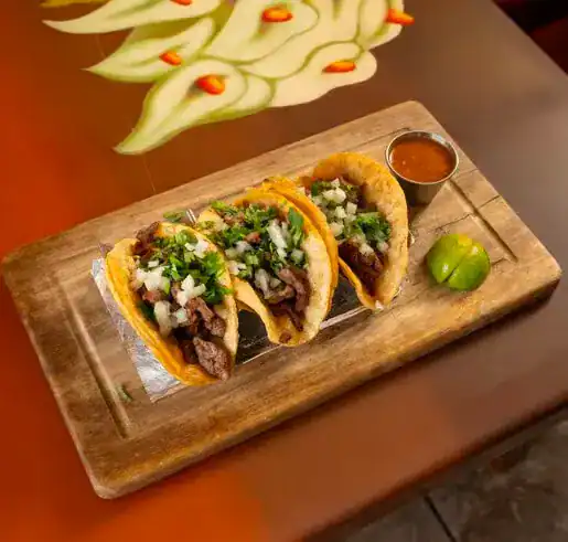 Delicious beef tacos topped with onions and cilantro, served with salsa and lime on a rustic wooden.