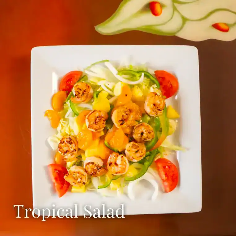 Fresh tropical salad with shrimp, tomatoes, and bell peppers on a white plate.