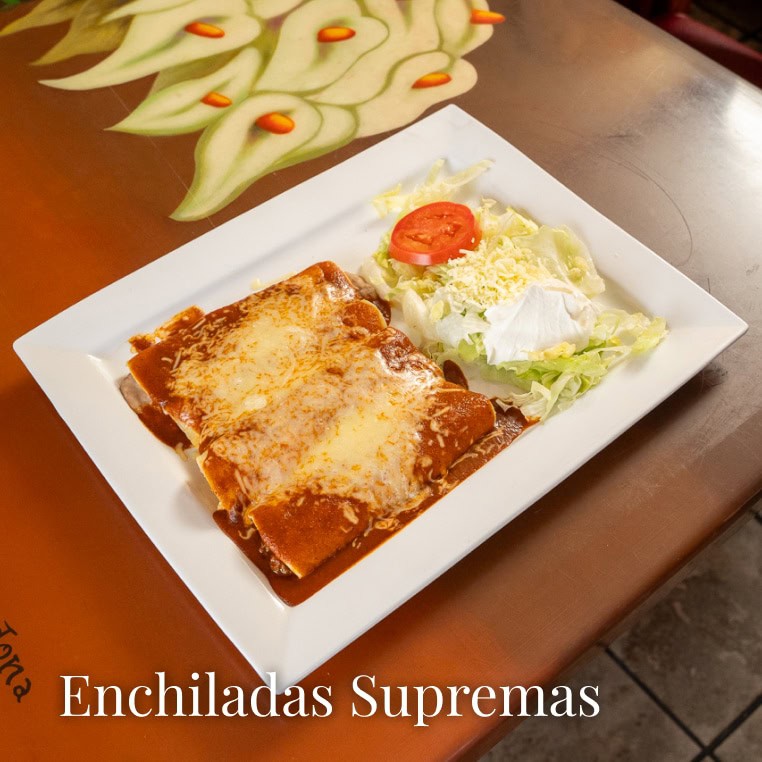 Delicious enchiladas supremas with melted cheese and fresh salad on a white plate.