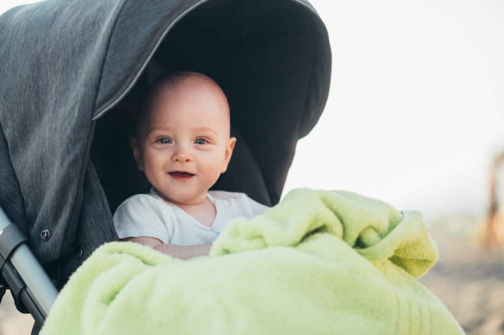Bebê sorrindo em seu carrinho durante passeio.