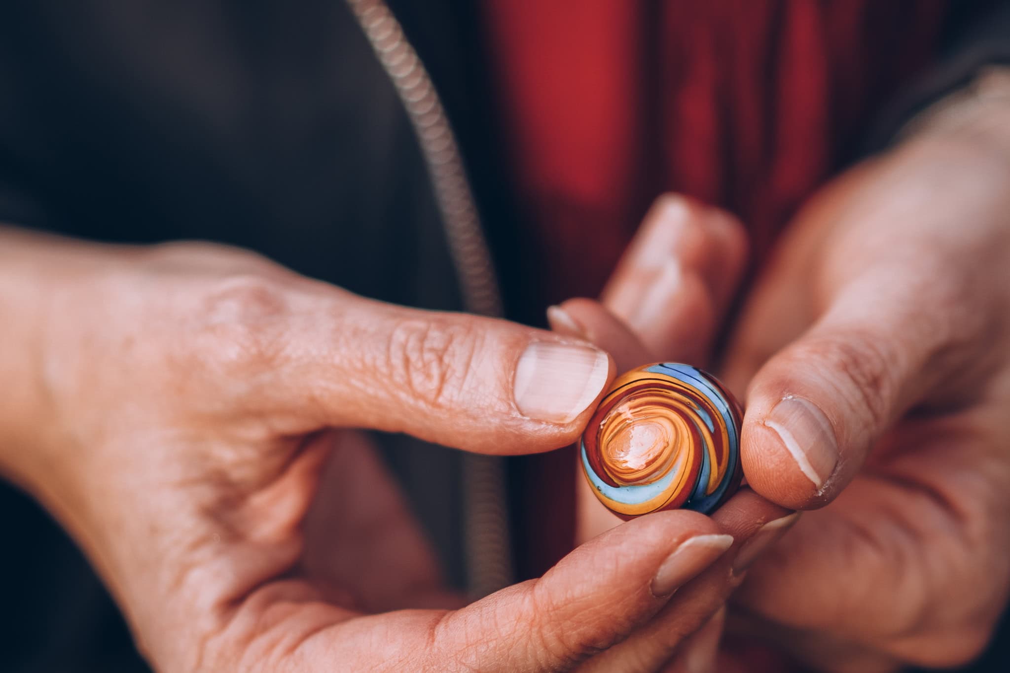 Jutta Nedden holds a colourful, swirling glass marble, showcasing her authentic presence.