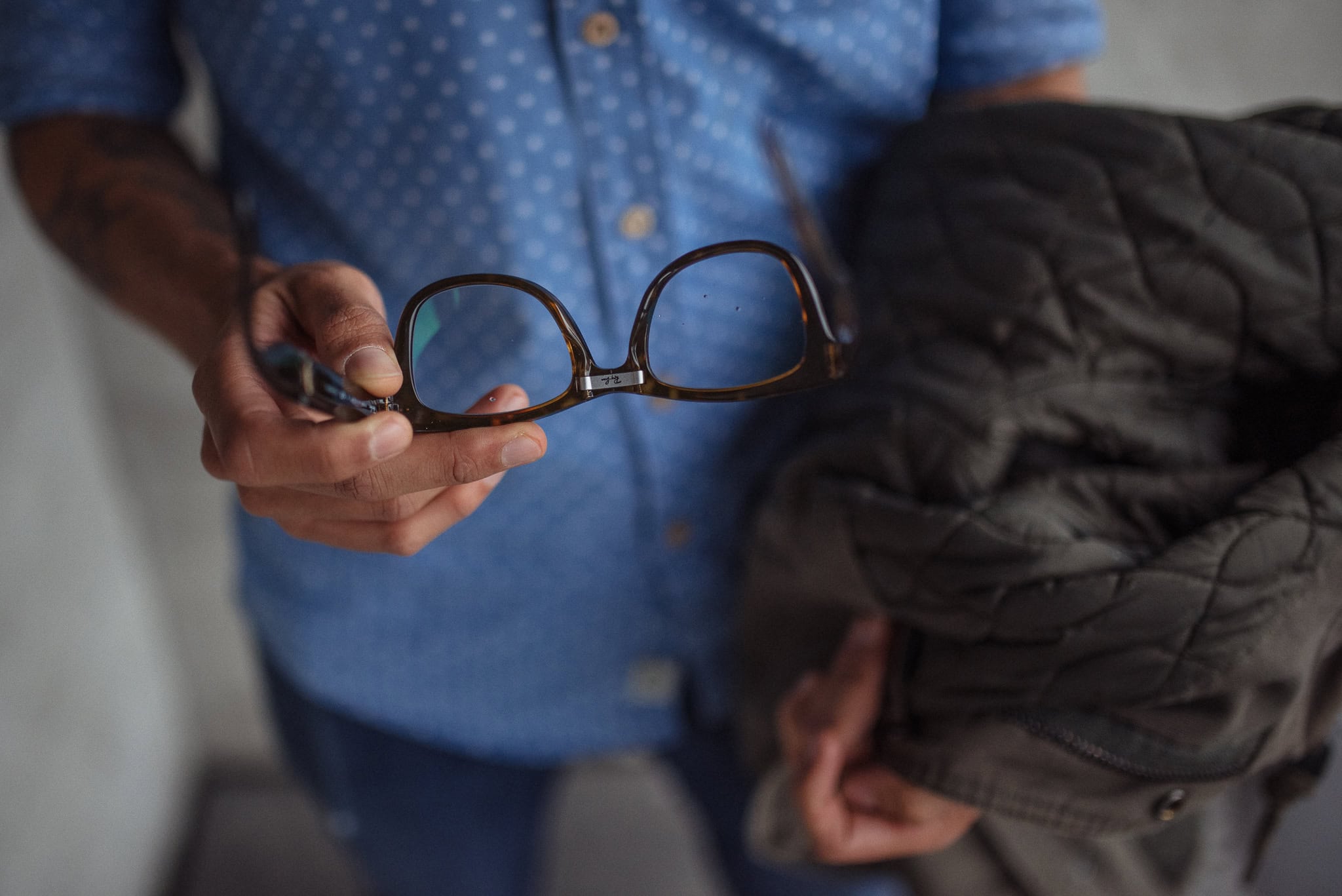 Cahit Ali, a coach, holds his glasses and jacket, ready for a London brand photography session.