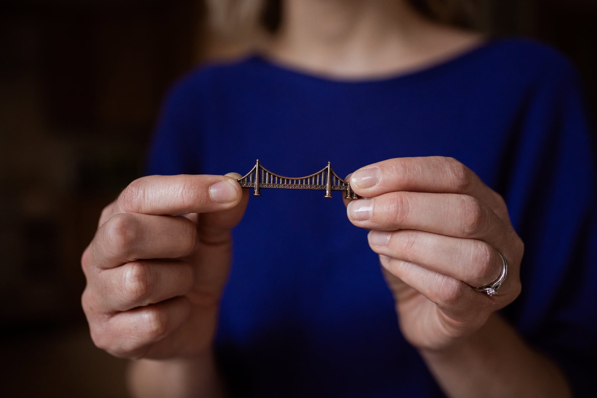 Claire Mackinnon holds a miniature golden bridge, a symbol of connection and progress in brand photography.
