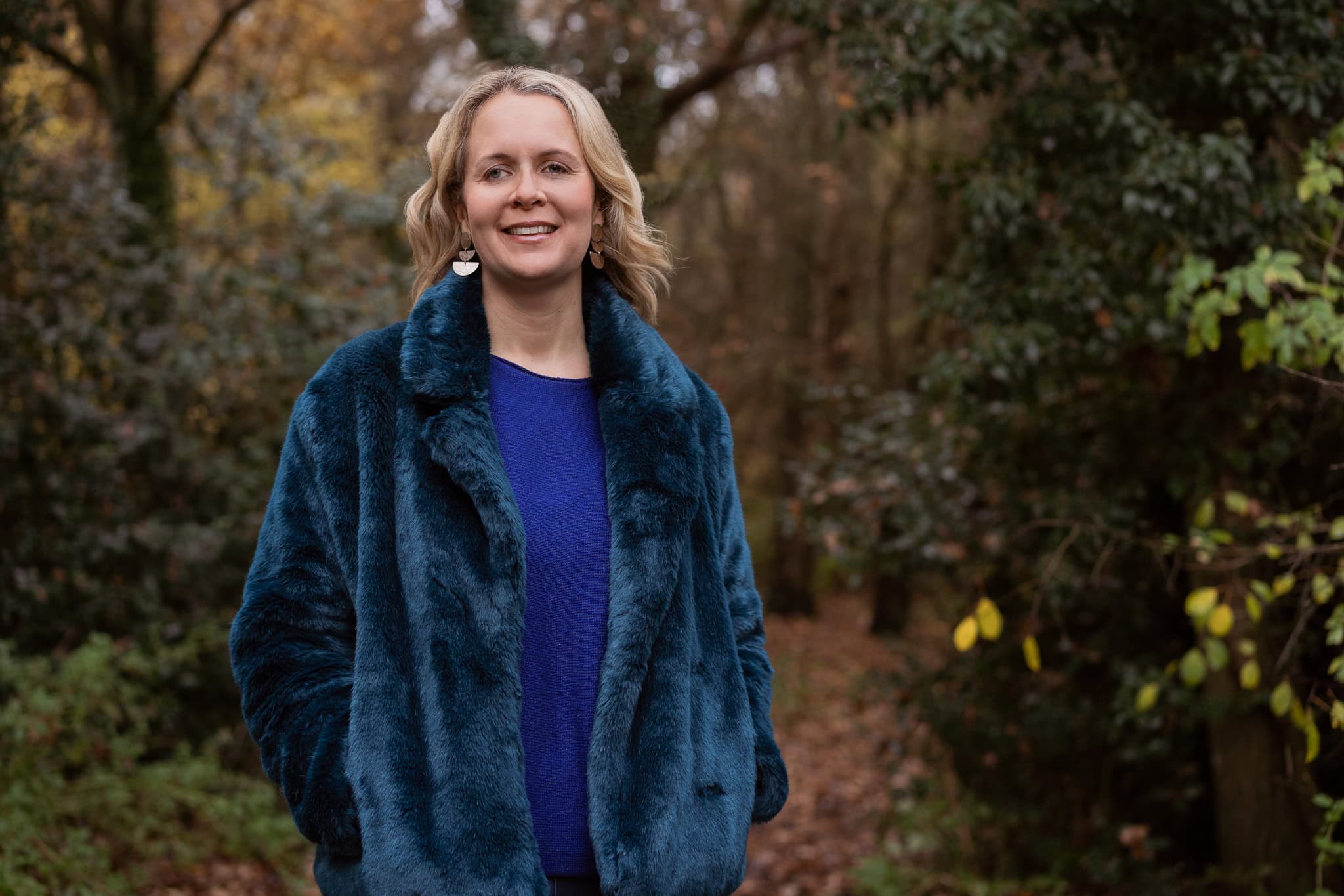 Claire Mackinnon, a confident woman, in a teal faux fur coat, photographed by a London brand photographer.