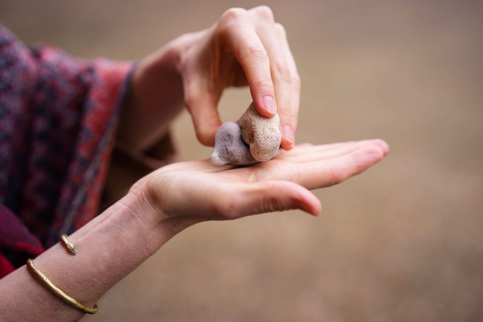 Close-up of Moni Soos's hands gently holding smooth stones, showcasing authentic connection.