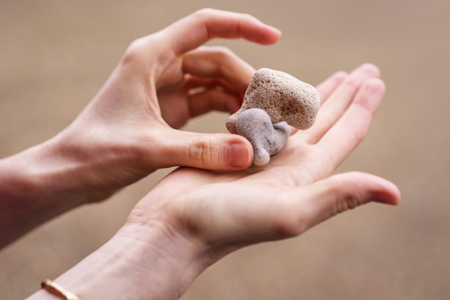 London brand photographer Phil Askew captures a close-up of hands holding unique, textured pebbles, showcasing authentic presence and natural light.