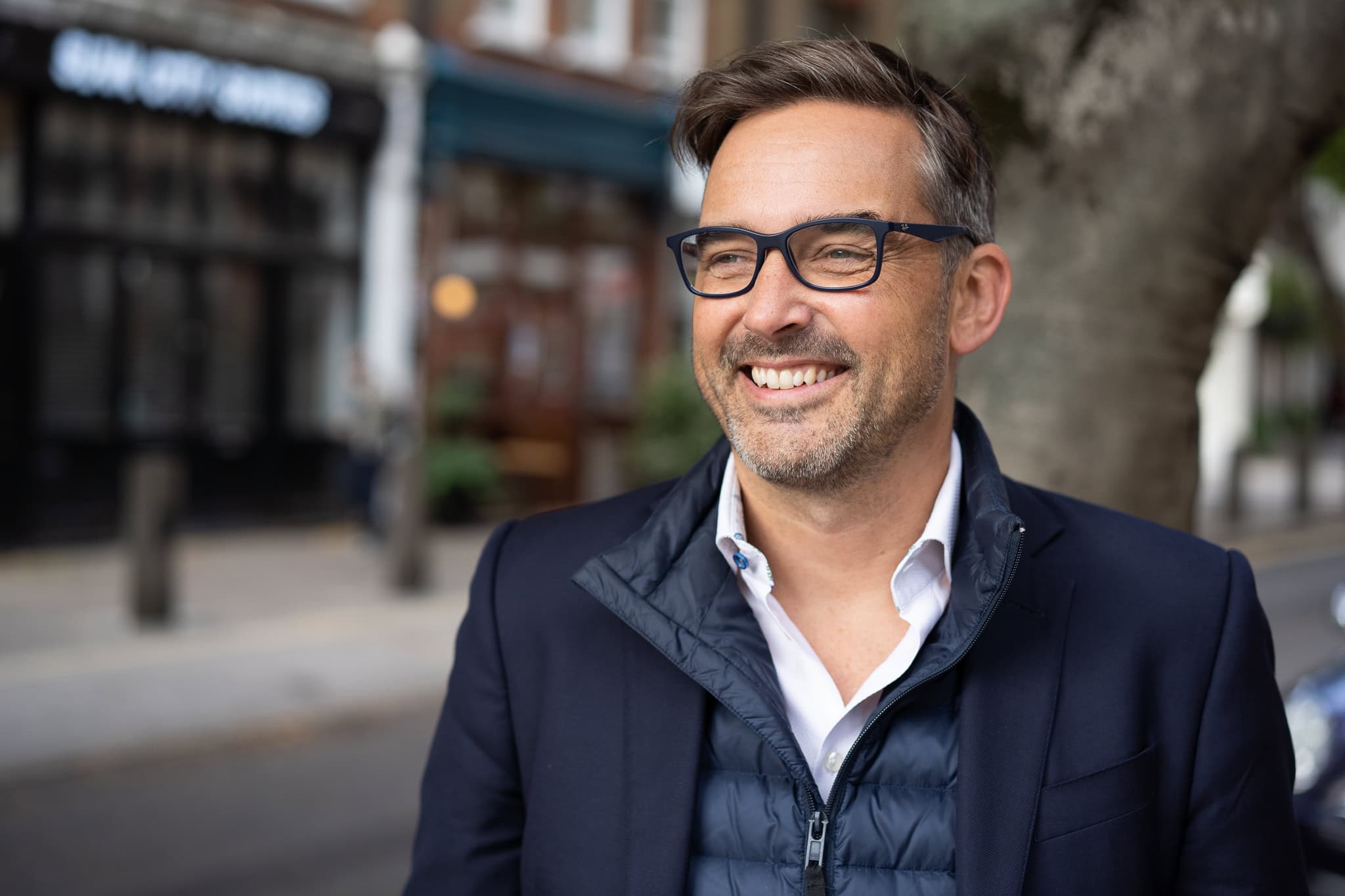 Zach Reynolds, a London brand photographer's subject, smiles authentically in natural light on a London street.