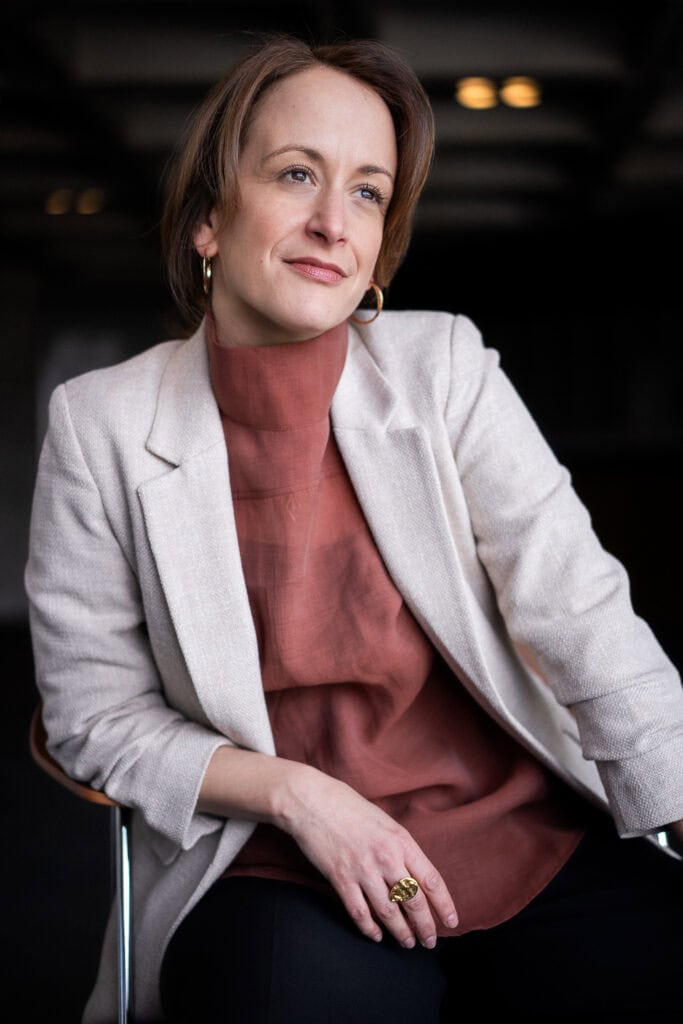 Confident female entrepreneur in a cream blazer and rust-colored top, professional brand photography for creative founders in London by Luminous Lives.