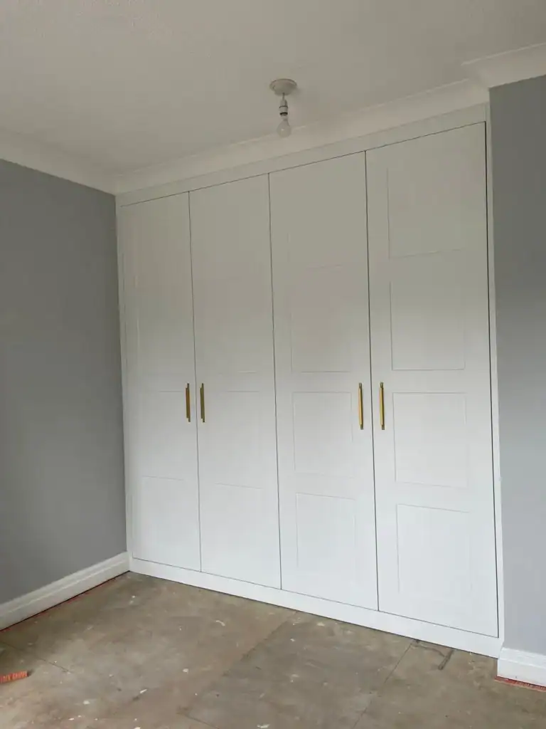 Built-in white wardrobes with personalised gold handles, designed by Made 2 Measure Interiors.