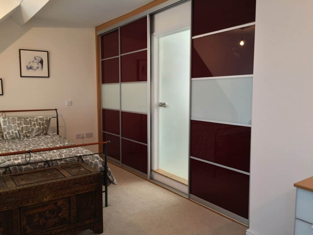 Customised sliding wardrobe with modern design and colour panels for space-efficient storage.