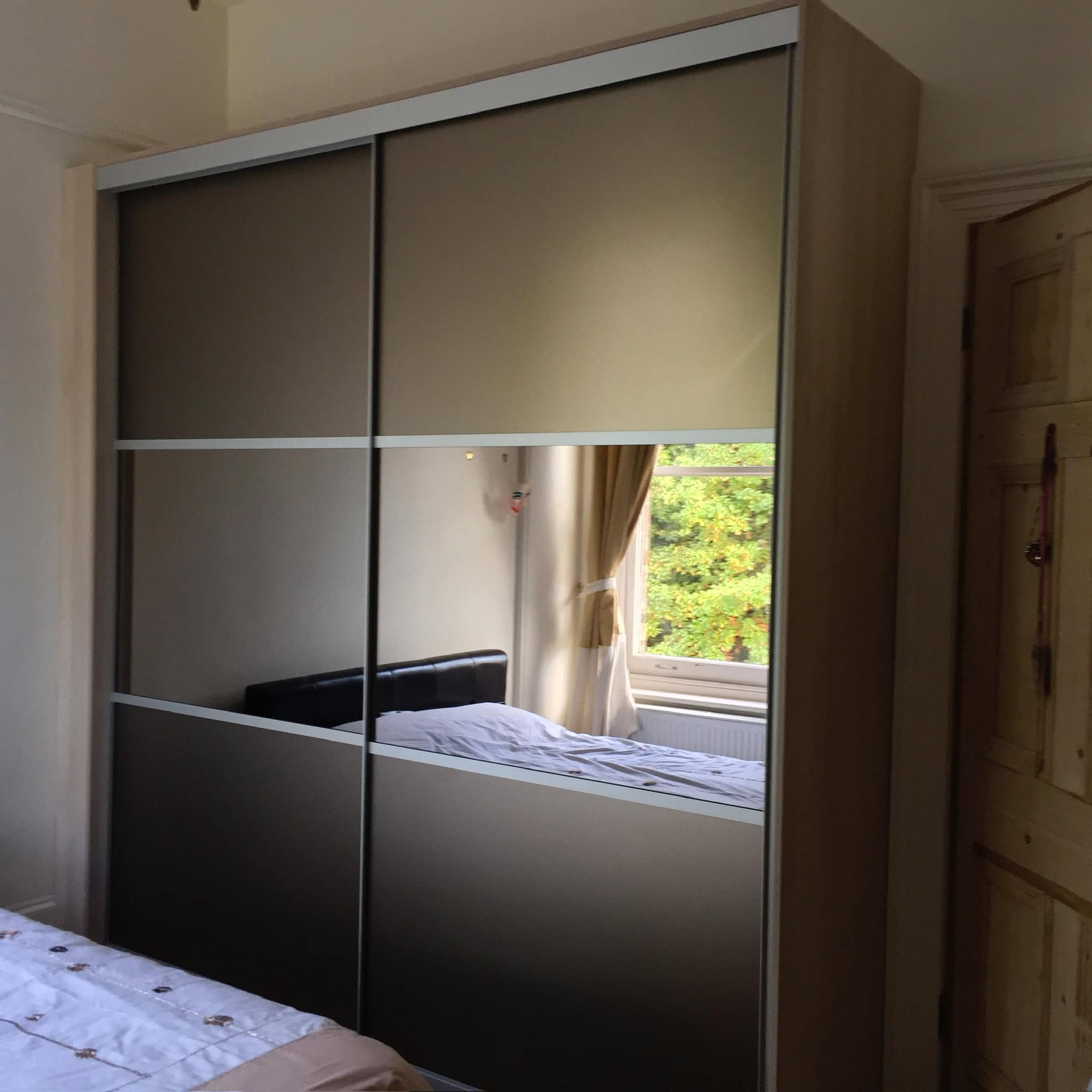 Custom fitted sliding wardrobe with modern mirror panels and beige doors for stylish storage solutions.