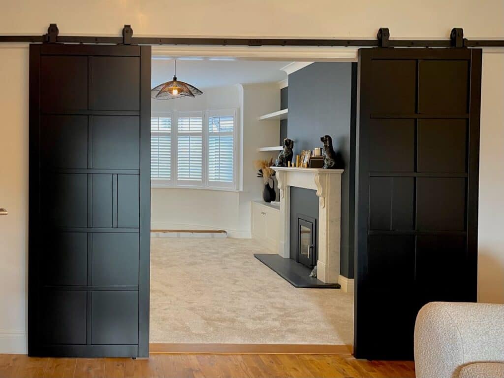 Contemporary black sliding barn door system in a modern living room interior.