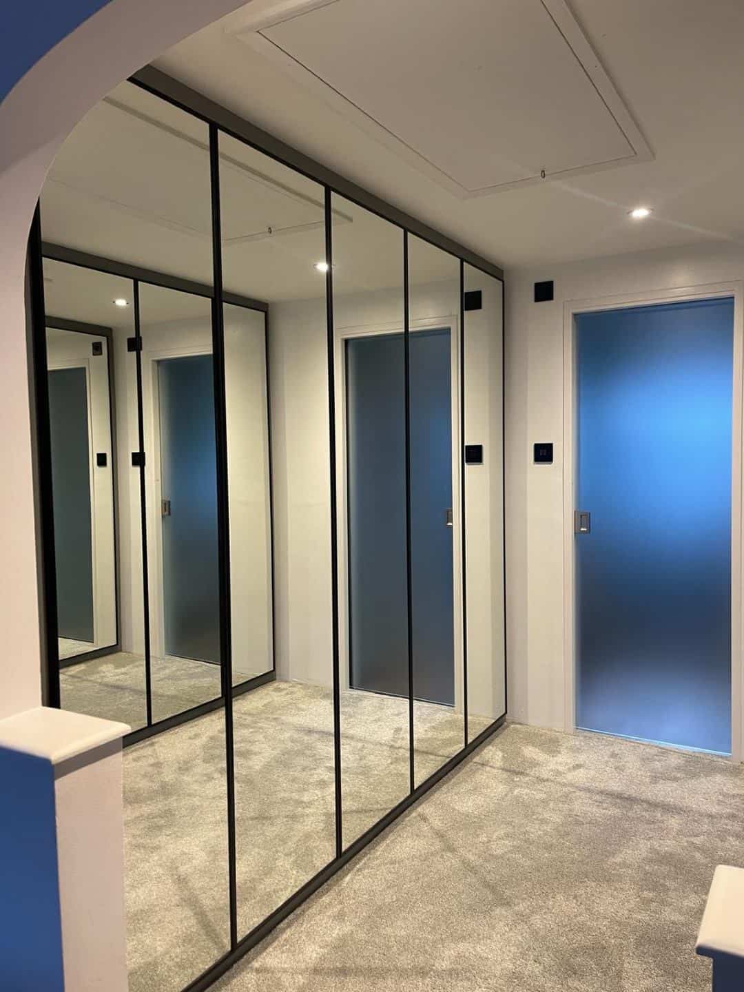 Mirrored sliding wardrobe doors with black frame for contemporary fitted interiors.