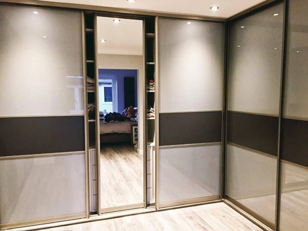 Stylish custom-made sliding wardrobe with mirrored doors and modern design for elegant bedroom storage.