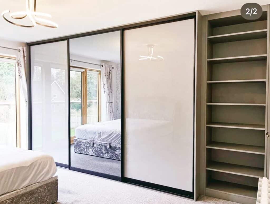 Contemporary built-in wardrobe with mirrored sliding doors and open shelving, custom-designed for functional storage.