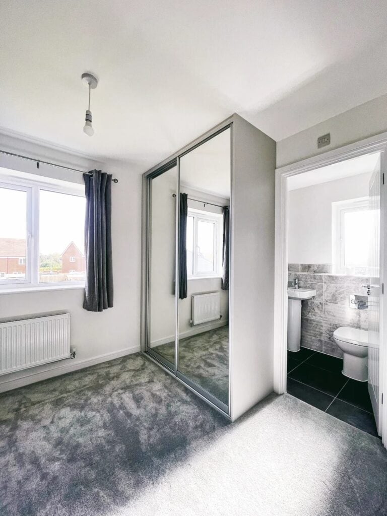Modern custom-built bedroom wardrobe with mirrored sliding doors, offering stylish storage solutions.