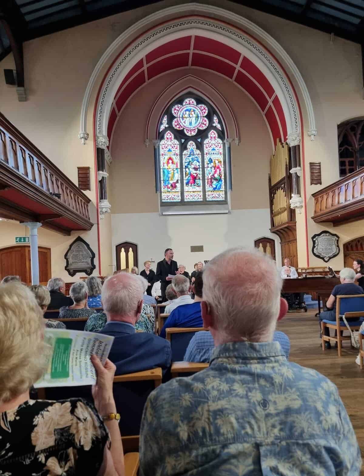Vibrant church interior with stained glass windows during a performance by Oriana Choir Macclesfield.