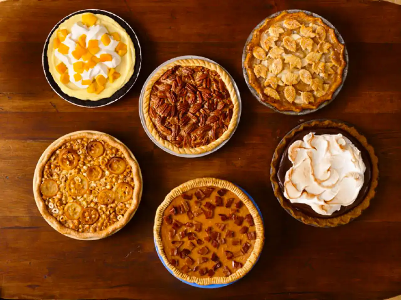Delicious variety of fruit and cream pies displayed on a rustic wooden surface.