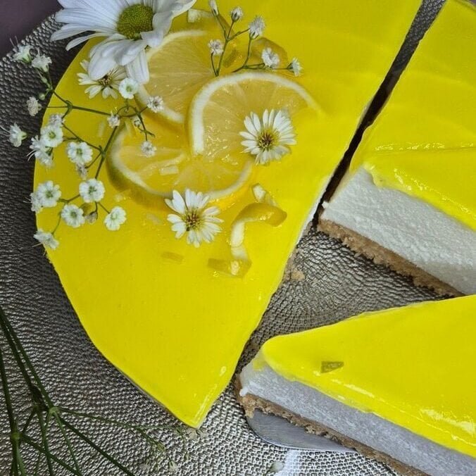 Bright lemon cheesecake topped with fresh lemon slices and edible flowers.