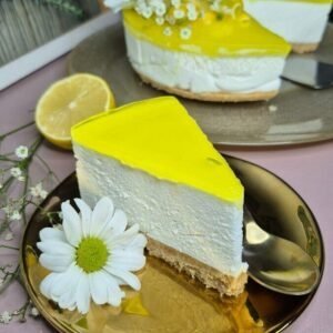 Fresh lemon cheesecake slice with bright yellow topping and decorative flower garnish.