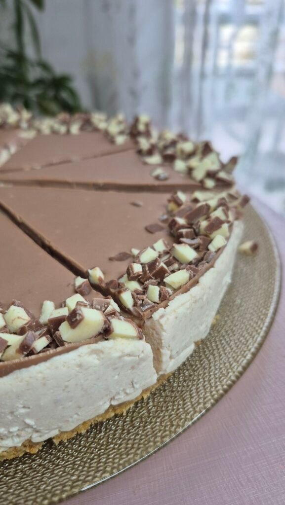 No-bake Kinder ricotta mascarpone cake sliced into wedges with chocolate topping and chopped Kinder on top