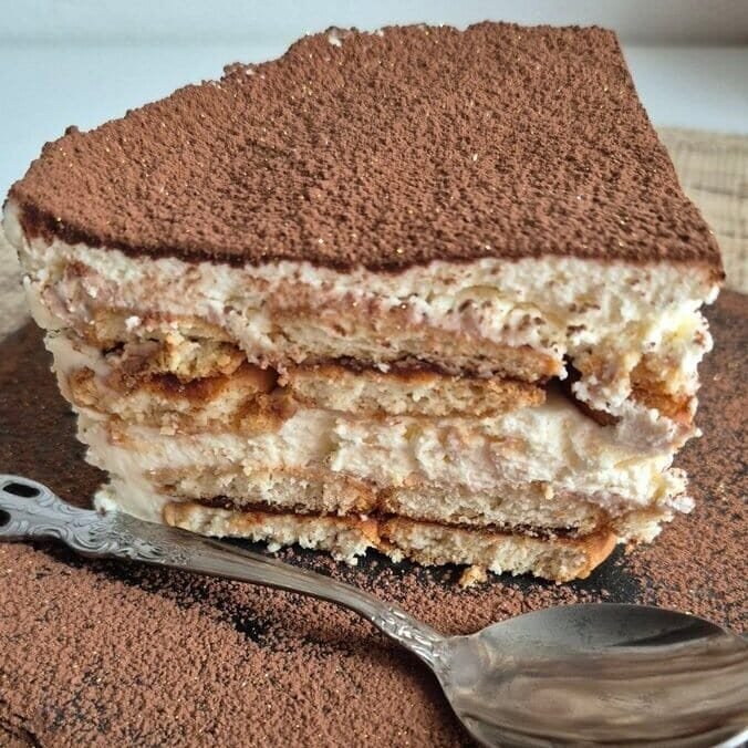 Slice of no-bake Nutella biscuit cake with mascarpone cream, dusted with cocoa powder.