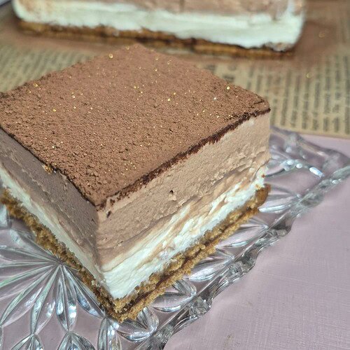 Two squares of no-bake Nutella biscuit cake with double mascarpone filling, dusted with cocoa powder