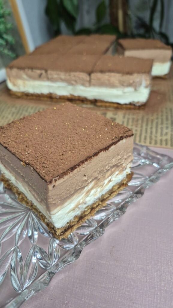 Two squares of no-bake Nutella biscuit cake with double mascarpone filling, dusted with cocoa powder