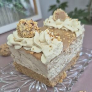 Creamy Giotto mascarpone cheesecake slice on a glass plate with whipped cream, hazelnuts, and a Giotto ball