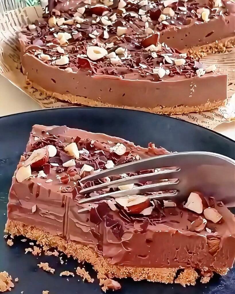 Delicious homemade chocolate hazelnut tart topped with chopped almonds and chocolate shavings. Perfect for any dessert lover.