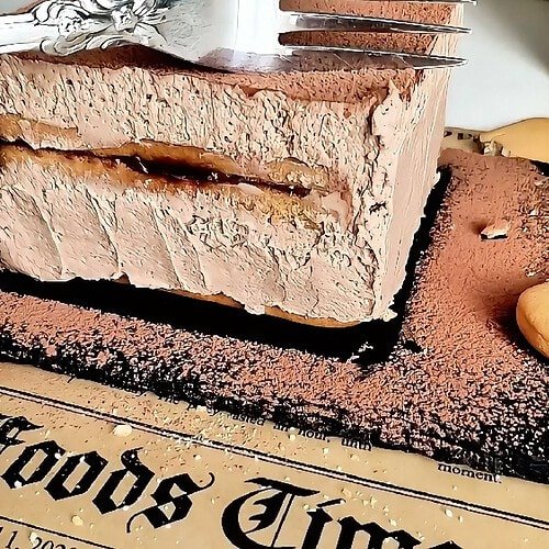 Slice of mini chocolate biscuit cake with Nutella cream layers and cocoa topping, with a fork resting on top.