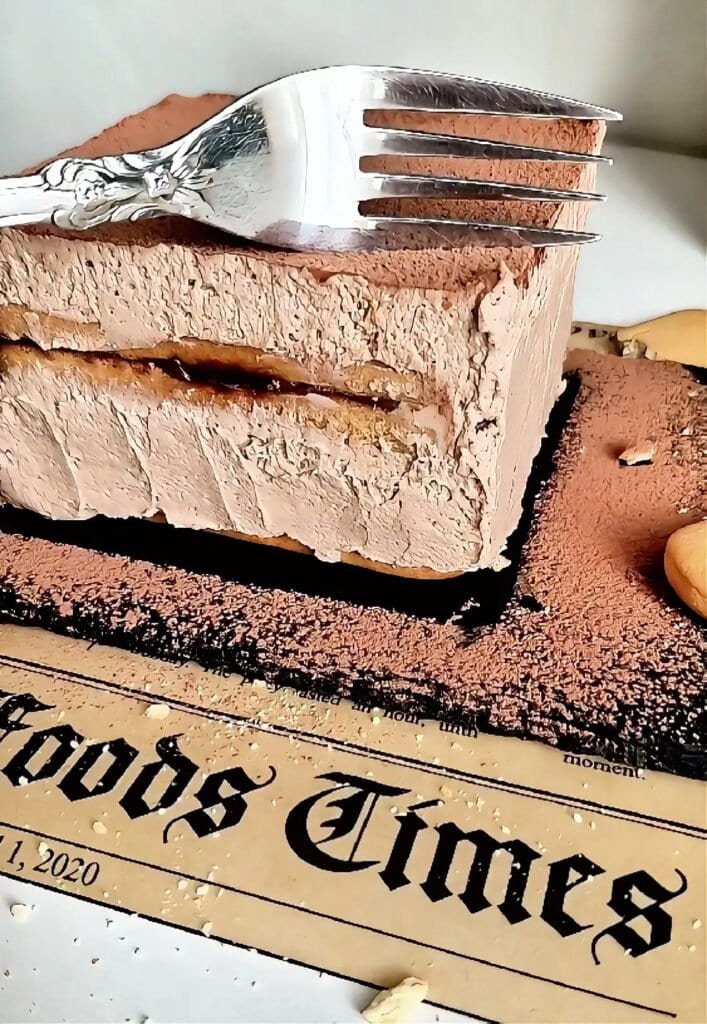 Slice of mini chocolate biscuit cake with Nutella cream layers and cocoa topping, with a fork resting on top.