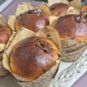 Freshly baked chocolate chip muffins in paper liners on a serving tray.