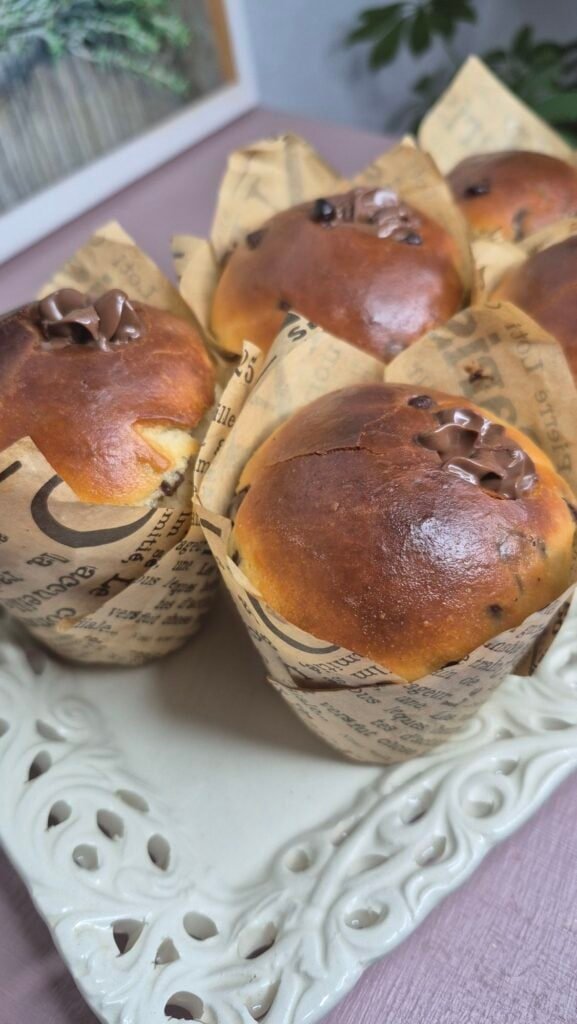 Golden brown chocolate chip yeast muffins in paper liners on a serving tray.
