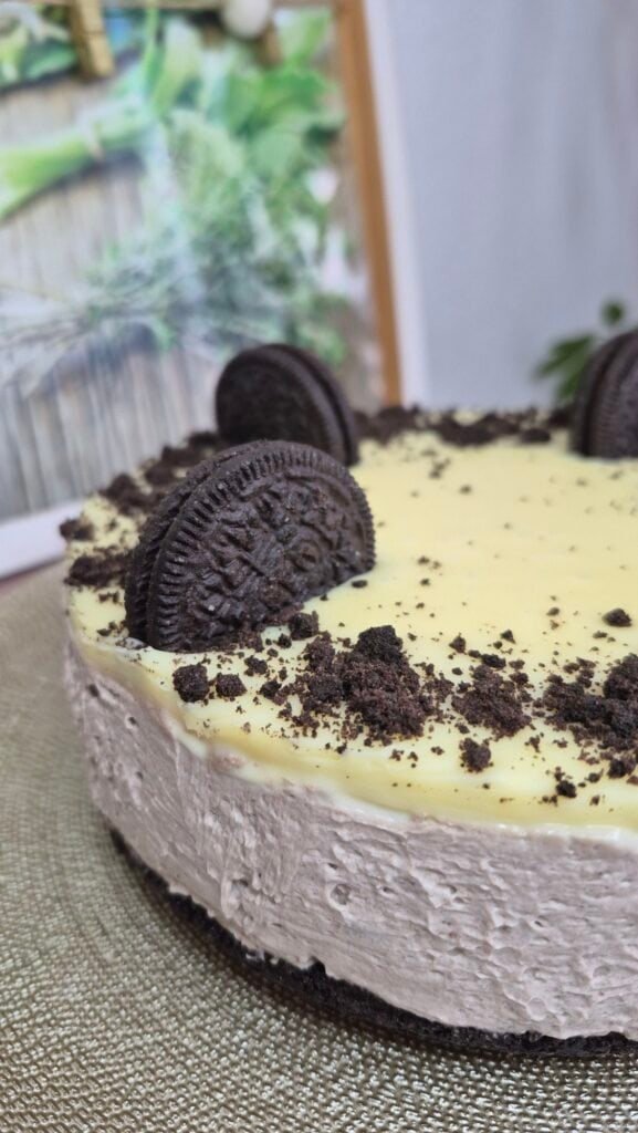 No-bake Oreo cake with mascarpone filling and white chocolate ganache, topped with Oreo crumbs and a whole Oreo cookie.
