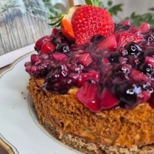 Homemade ricotta cheesecake with glossy mixed berry topping, topped with fresh strawberries