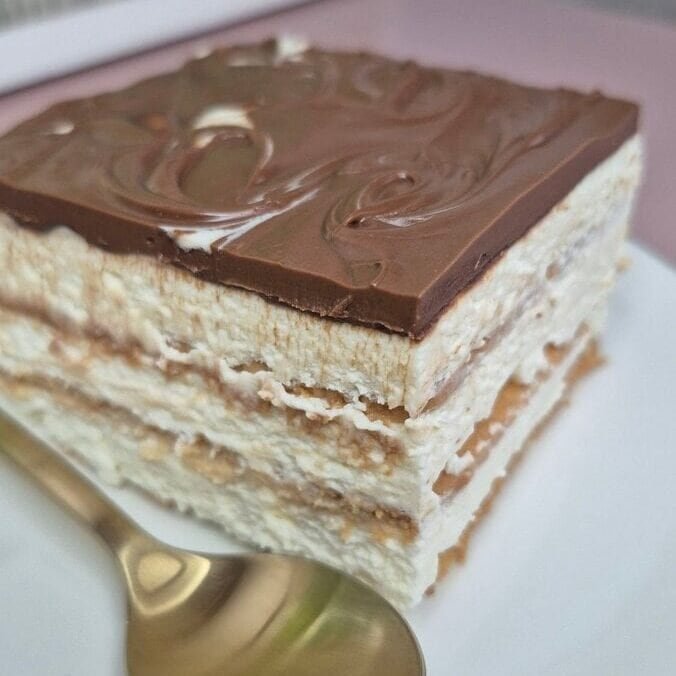 Slice of no-bake petit beurre biscuit cake with mascarpone cream and Nutella topping on a plate.