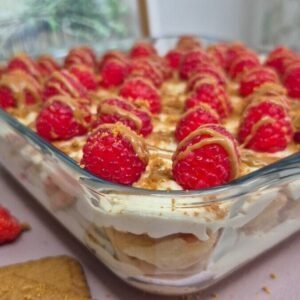 Whole Lotus Biscoff raspberry tiramisu topped with fresh raspberries in a glass dish.